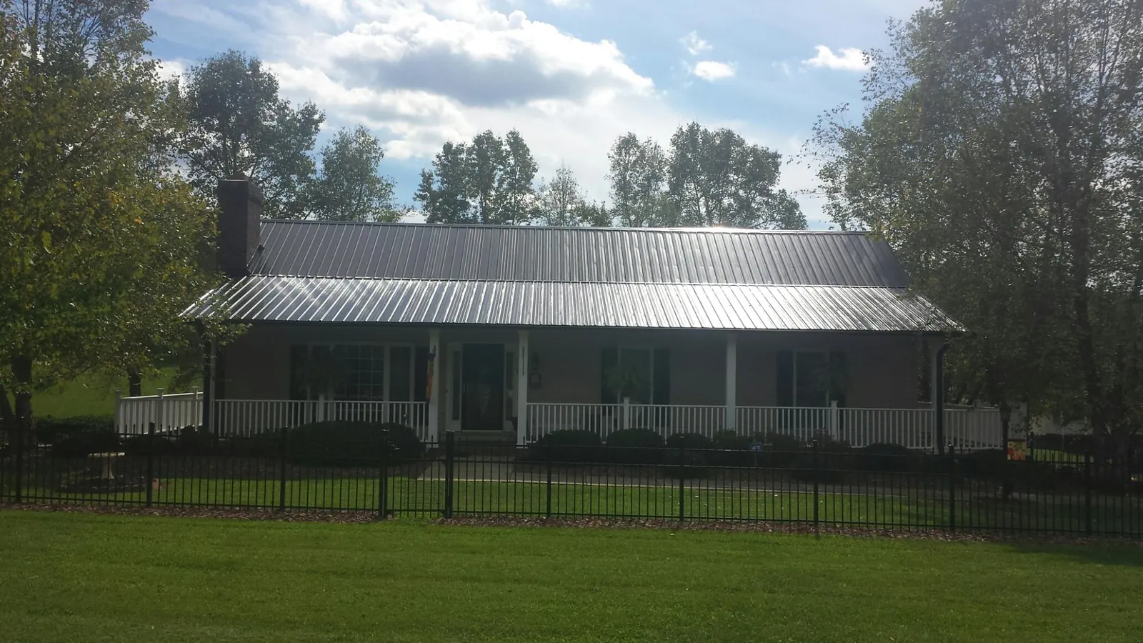 Gray metal roof on a brick ranch with a full width front porch — Gutter Guard Installation work by our crew in Brownsville